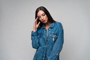 hermosa caucásico niña en un mezclilla chaqueta posando en el estudio en un blanco antecedentes. foto