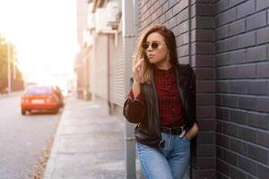 hermosa joven elegantemente vestido caucásico niña fuma cigarrillo en el calle. foto