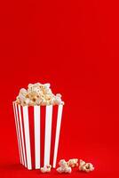 Glass with popcorn on a red background photo