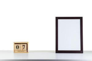 Wooden calendar 07 January with frame for photo on white table and background