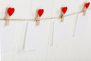 white pieces of paper on clothespins with a heart on a wooden background photo