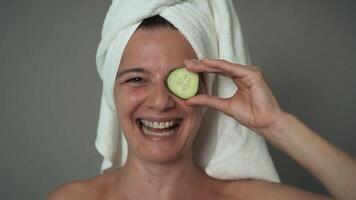 a woman is holding a cucumber to her face video