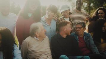 a group of people from different generation are sitting on the grass in a park video