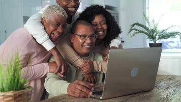 un familia de cuatro es sonriente mientras mirando a un ordenador portátil video