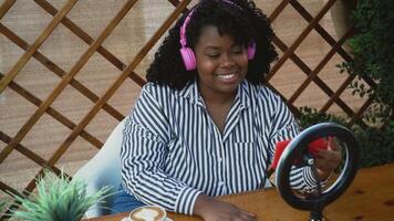 a woman wearing headphones sits at a table with a laptop video