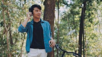 A man pushes a bicycle and walks happily to relax in the park after cycling for exercise. video