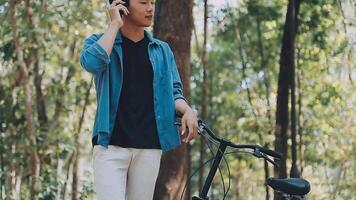 A man pushes a bicycle and walks happily to relax in the park after cycling for exercise. video