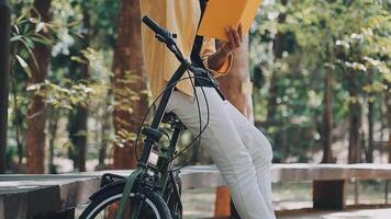 un hombre empuja un bicicleta y camina felizmente a relajarse en el parque después ciclismo para ejercicio. video