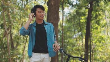 A man pushes a bicycle and walks happily to relax in the park after cycling for exercise. video