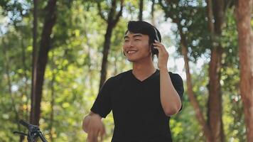 A man pushes a bicycle and walks happily to relax in the park after cycling for exercise. video