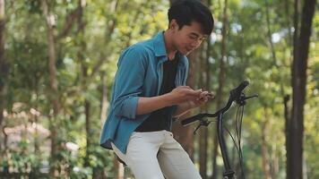 A man pushes a bicycle and walks happily to relax in the park after cycling for exercise. video