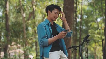 A man pushes a bicycle and walks happily to relax in the park after cycling for exercise. video