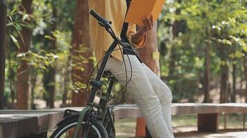 un hombre empuja un bicicleta y camina felizmente a relajarse en el parque después ciclismo para ejercicio. video