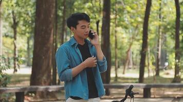 A man pushes a bicycle and walks happily to relax in the park after cycling for exercise. video