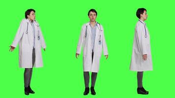 Physician being uncertain about something in studio, shrugging and feeling clueless about the right answer. Doctor doing i dont know symbol against greenscreen backdrop, confusion. Camera A. video