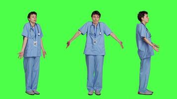 Medical assistant shrugging and doing i dont know sign in studio, acting clueless and uncertain against greenscreen backdrop. Nurse in scrubs gesticulating doubtful reaction, unsure girl. Camera B. video