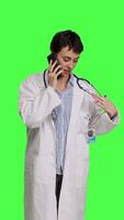 Front view Woman doctor talking on smartphone call against greenscreen backdrop, answering phone line to make an exam appointment for a patient. Physician uses mobile phone to chat with people. Camera B. video