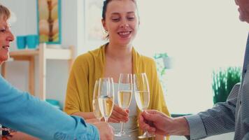 contento extendido familia disfrutando un vaso de vino champán. personas de dos generaciones hablando, sentado alrededor el mesa tostado y celebrando un evento Bebiendo un vaso de blanco vino. video