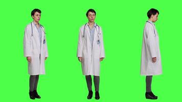 Physician saying no and showing negative reaction symbol in studio, wearing a white coat and standing against greenscreen backdrop. Woman medic feeling displeased, rejection sign. Camera A. video