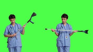 Hospital staff worker assembling crutches to help with mobility and healing, preparing walking tool for someone with broken leg. Medical assistant helping patient with fracture. Camera B. video