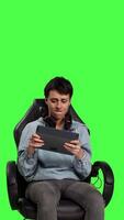 Front view Displeased gamer feeling sad about losing video games championship, playing e sport tournament on tablet against greenscreen backdrop. Frustrated angry woman with gaming failure. Camera B.