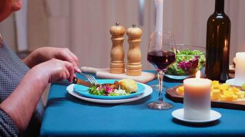 vicino su di mangiare sano cibo a cena, nel il cucina, seduta a il tavolo. anziano vecchio donna, godendo il pasto, festeggiare loro anniversario nel il cenare camera video