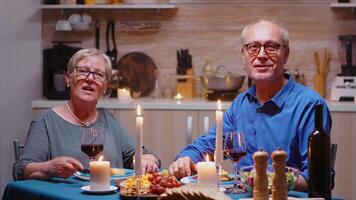 idosos casal tendo uma vídeo ligar dentro a cozinha durante romântico jantar, comendo festivo refeição. pov conectados Internet moderno conferência, conversando, comunicação, bate-papo conversação ligar através da Webcam video