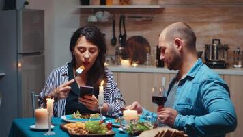 Surfen auf Telefone während Abendessen Paar halten Smartphones Sein im das Küche Sitzung beim das Tabelle durchsuchen, suchen, mit Smartphones, Internet, feiern ihr Jahrestag im das Essen Zimmer. video