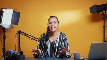 New media star talking to the camera and recording a new episode of her show. Content creator influencer on social media recording for internet web online subscribers audience new podcast with microphone in professional studio video