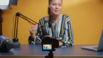 Selective focus on camera while social media star records an new podcast episode in her professional studio. Content creator new media influencer recording for internet web online subscribers audience video