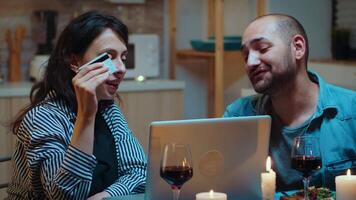 Husband and wife shopping online and making payments during dinner using card. Couple sitting at the table, searching, browsing, surfing, using technology, enjoying festive meal in the dining room video