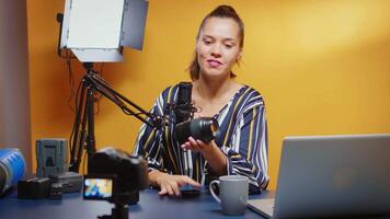 Influencer showing her public a new camera lens and reviewing it in professional studio set. Content creator new media star influencer on social media talking video photo equipment for online internet web show