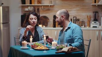 joven casado Pareja teniendo gracioso momentos a cena. esposa y marido durante romántico cena en el cocina, comida juntos a hogar, disfrutando el comida, celebrando su aniversario, sorpresa fiesta video