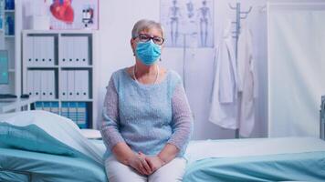 solitário Senior mulher dentro hospital cama vestindo uma protetora mascarar, esperando para coronavírus resultado. global saúde crise, médico sistema durante pandemia, doente idosos paciente dentro privado hospital ou clínica video