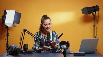 Smiling videography expert showing to the camera ways to mount fluid head plate. Influencer making online internet content about video equipment for web subscribers and distribution, digital vlog talking film