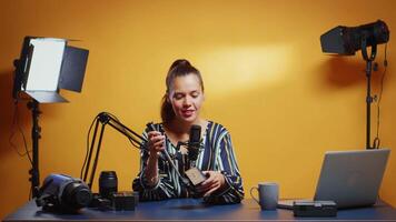 Social media star presenting a fluid tripod head in her professional studio. Influencer making online internet content about video equipment for web subscribers and distribution, digital vlog