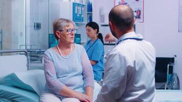 enfermero trayendo radiografía resultados de antiguo retirado mayor mujer a médico en privado clínica o hospital. salud cuidado pantalla médico medicina diagnóstico de enfermedad tratamiento. radiología oficina especialista video