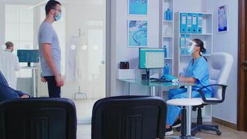 Patient with face mask against coronavirus at hospital reception asking nurse for direction. Handicapped senior woman in wheelchair with sterile face protection against covid-19. video