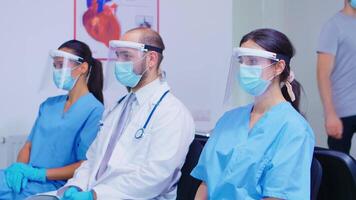 stanco squadra di medico personale con viso maschera e visiera contro coronavirus scoppio nel ospedale in attesa la zona. paziente entrata nel ospedale atrio. medico indossare stetoscopio. video