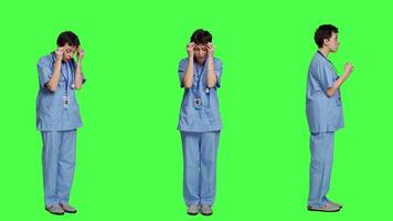 Stressed furious nurse screaming at someone against greenscreen backdrop, showing rage and anger in studio. Aggressive upset medical assistant shouting and being dissatisfied. Camera A. video