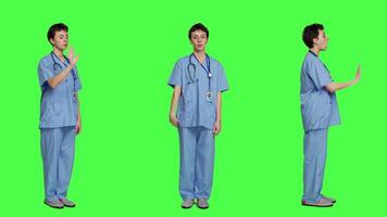 Health specialist with blue scrubs showing stop sign in studio, standing against greenscreen backdrop. Nurse expressing denial and refusal with warning forbidden symbol, denying something. Camera A. video