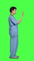 Profile Medical assistant asking a person to come over closer against greenscreen backdrop, inviting patient to approach. Nurse in scrubs calling someone at checkup examination, young surgeon. Camera A. video