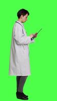 profil général praticien en train d'étudier radiographie analyse résultats pour les patients avec maladie, des stands contre écran vert toile de fond. médical examine X rayon diagnostic, travaux avec une tablette. caméra un. video