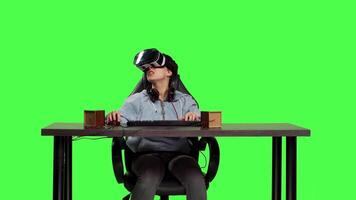 Disappointed player losing at video games shooter competition with virtual reality headset, playing contest on computer against greenscreen. Sad frustrated woman being displeased. Camera B.