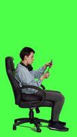 Profile Woman focusing on online videogames tournament with tablet, sitting on chair against greenscreen backdrop. Gamer playing e sport championship for a shooter game, digital device graphics. Camera A. video