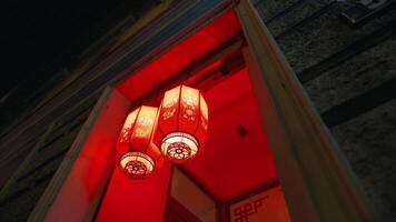 iluminado bem-vinda. simétrico exibição do dois vermelho lanternas convida convidados para dentro a restaurante video