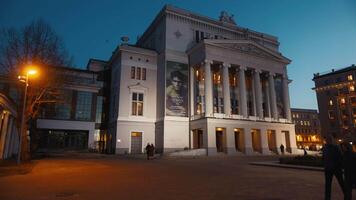 28 febbraio, 2024 - riga, Lettonia. un' mille dollari bianca edificio con colonne si illumina il notte cielo - lettone nazionale musica lirica nel riga video