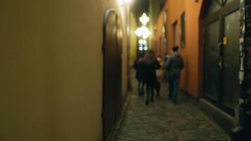 borroso imagen de personas caminando en guijarro callejón a noche video