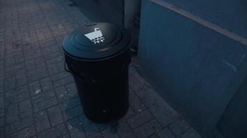 a black trash can with a sticker on the lid is sitting on a sidewalk next to a building video