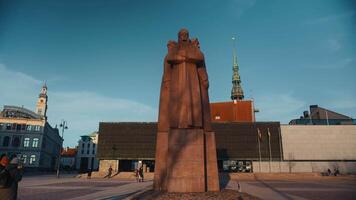 28 februari, 2024 - riga, lettland. staty av en man förbi en byggnad i stad fyrkant, mot molnig himmel video